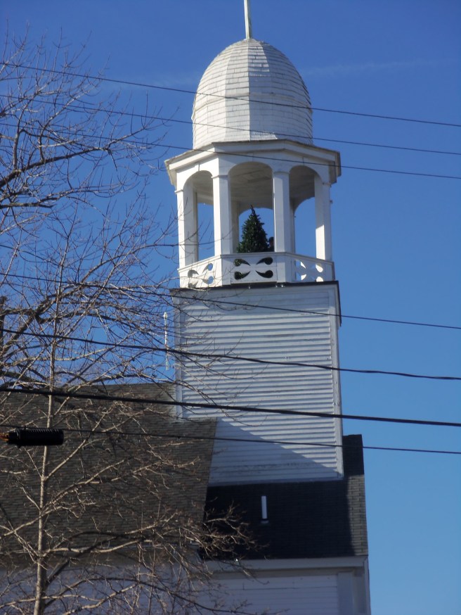 Look closely to the left of the Christmas tree and you can see one of the men who had just placed it there in the cupola of a former church on the square at York Village.